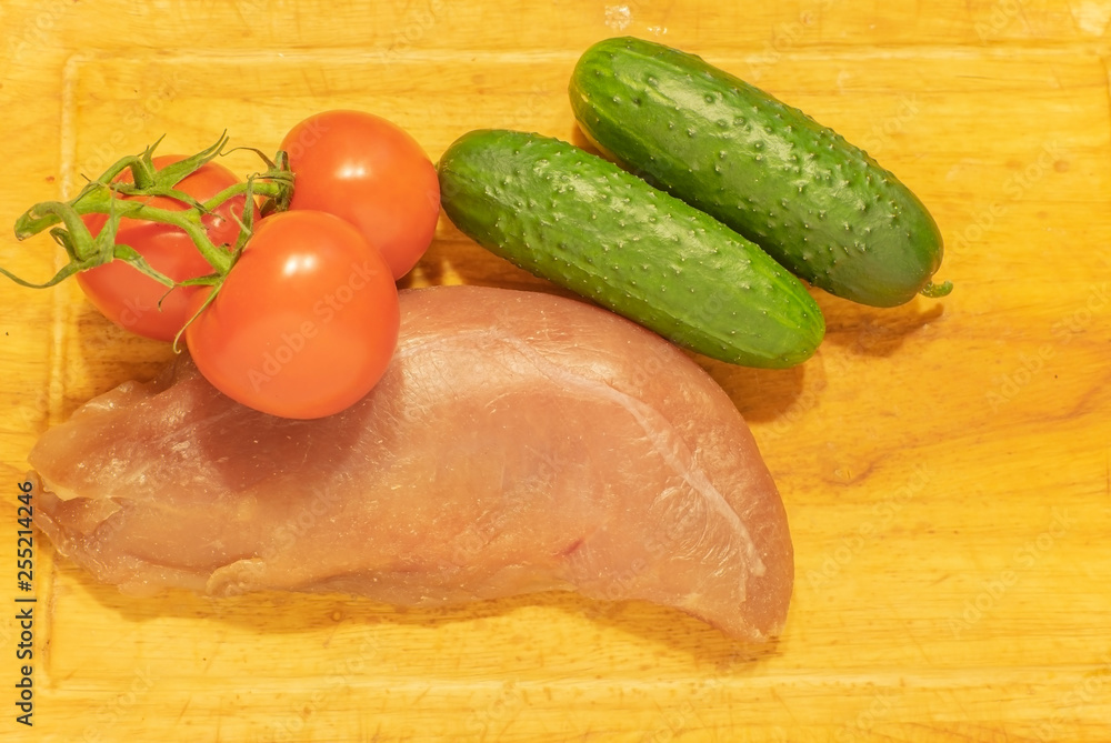 Raw duck breast with tomatoes and cucumbers. On the chopping Board. Raw duck breast with tomatoes and cucumbers. On the chopping Board.