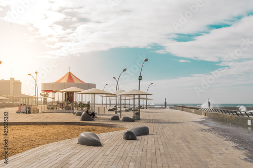 View of Namal promenade at Tel Aviv Port, Israel. Sunset at harbour deck with carousel and sunshades by the sea.