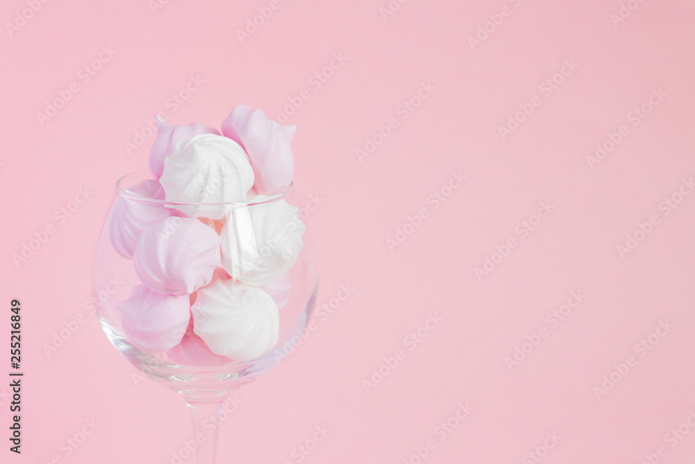 White and pink twisted meringues in a vine glass on pink background. French dessert prepared from whipped with sugar and baked egg whites. Greeting card with copy space White and pink twisted meringues in a vine glass on pink background. French dessert prepared from whipped with sugar and baked egg whites. Greeting card with copy space
