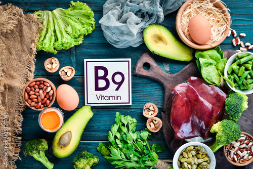 Foods that contain natural vitamin B9: Liver, avocado, broccoli, spinach, parsley, beans, nuts, on a blue background. Top view. photo