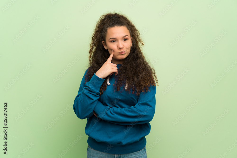 Teenager girl over green wall thinking Teenager girl over green wall thinking