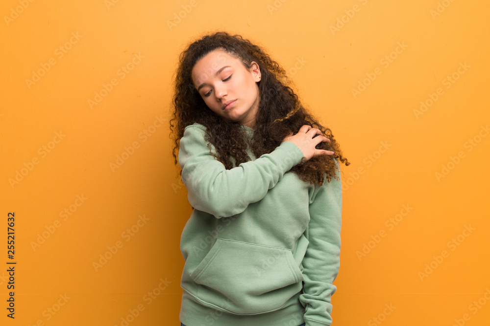 Teenager girl over ocher wall suffering from pain in shoulder for having made an effort Teenager girl over ocher wall suffering from pain in shoulder for having made an effort