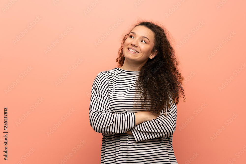 Fototapeta premium Teenager girl over pink wall looking up while smiling