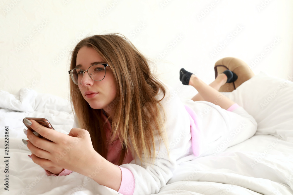 Teenager with smartphone lying on bed Teenager with smartphone lying on bed