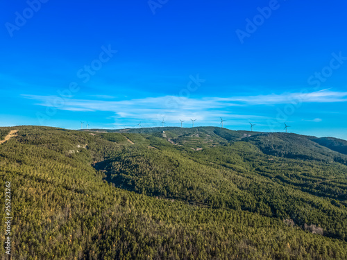Aerial view of drone, forest in mountain with wind turbines on ridge