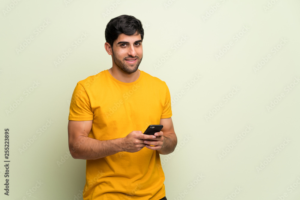 Young man over pink wall sending a message with the mobile Young man over pink wall sending a message with the mobile