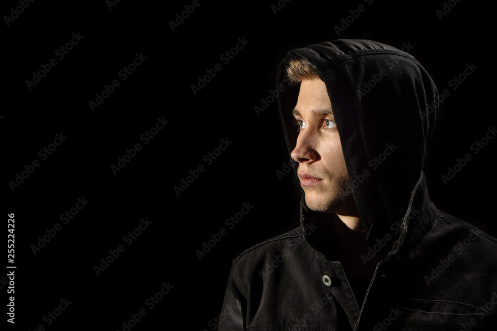 Portrait of a young man in the hood black background Portrait of a young man in the hood black background