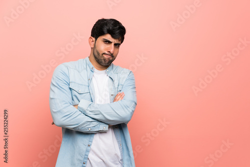 Young man over pink wall feeling upset