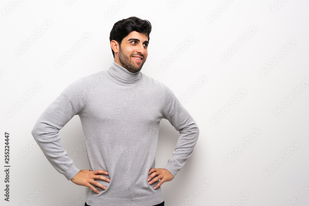 Fototapeta premium Young man over isolated white wall posing with arms at hip and smiling