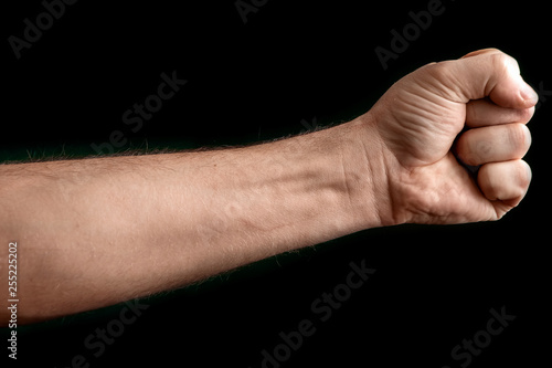 Fist isolated on black background. A strong man raised his fist on a black background, power, protest, fist ready for battle. © Aliaksandr Marko