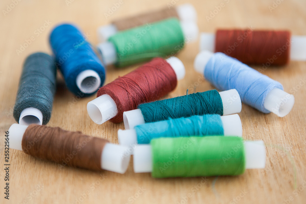 Multicolored sewing threads on the wood ground Multicolored sewing threads on the wood ground