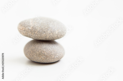 Two pebbles against each other on the white ground