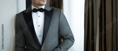 Foto Man model in expensive custom tailored tuxedo, suit standing and posing indoors