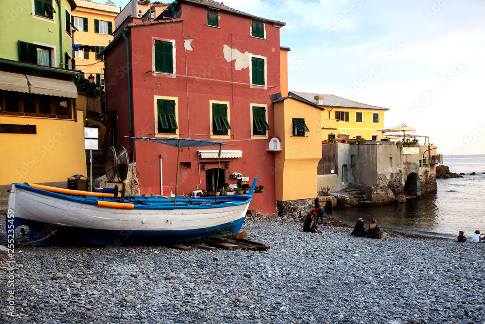 Obraz premium old boat on the sea on the background of old Italian houses in the city of Genoa on a warm summer evening