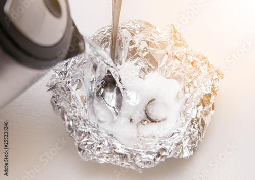 A solution of baking soda(Sodium bicarbonate) and warm water will remove the tarnish from silver when the silver is in contact with a piece of aluminium tin foil. Silver jewellery in baking soda.