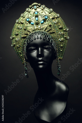 Black head of mannequin in decorated green kokoshnick, dark studio background