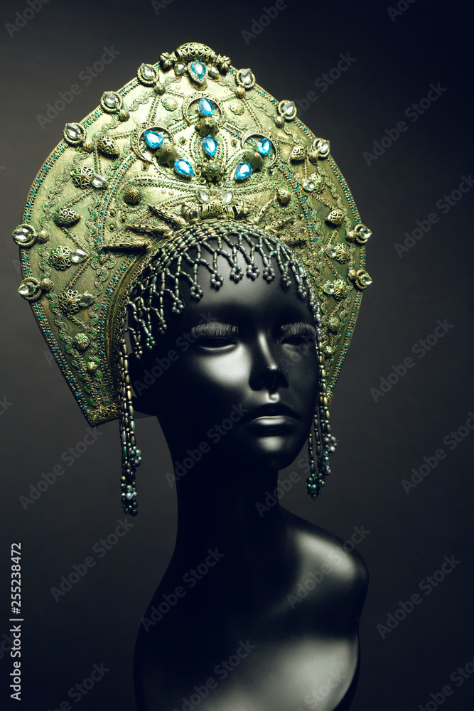 Black head of mannequin in decorated green kokoshnick, dark studio background Black head of mannequin in decorated green kokoshnick, dark studio background