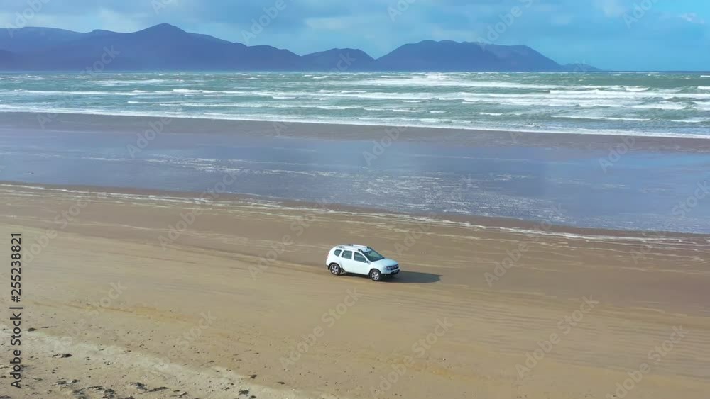 Aerial 4k view of car driving on beautiful beach. SUV driving on Inch Beach in Ireland Aerial 4k view of car driving on beautiful beach. SUV driving on Inch Beach in Ireland