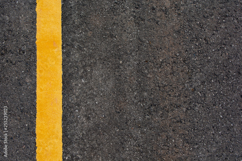 Yellow line on black asphalt road background with copy space