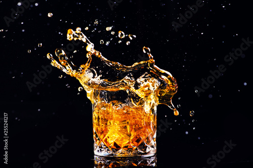 whiskey with splash on black background, brandy in a glass