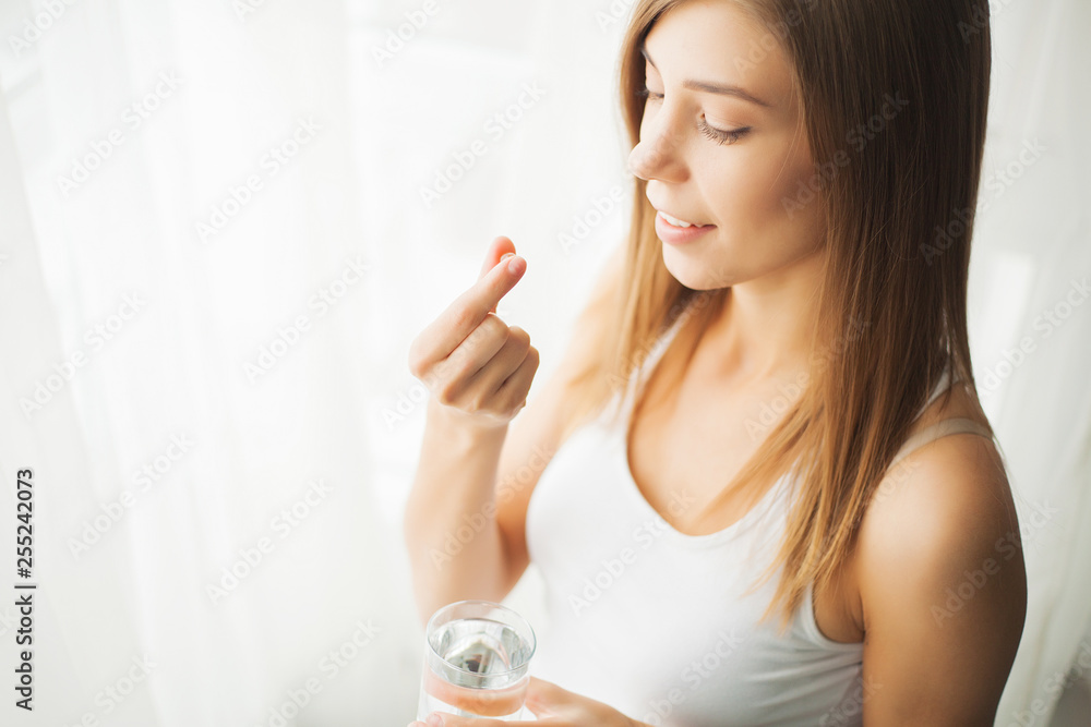 Health concept. Young woman holding pill and glass of water Health concept. Young woman holding pill and glass of water
