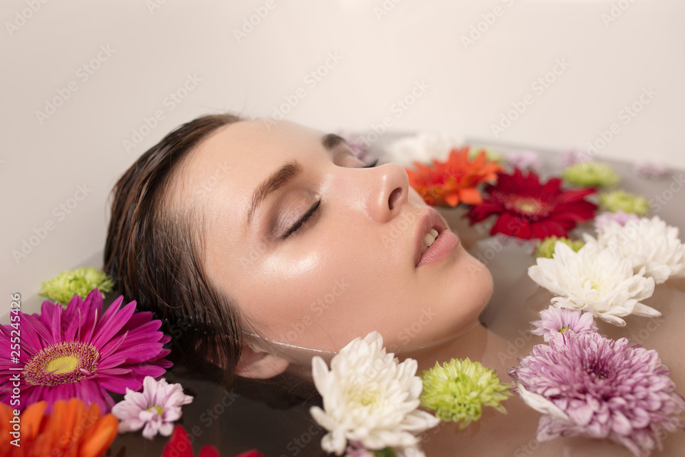 Young woman relaxing in bath with flowers.