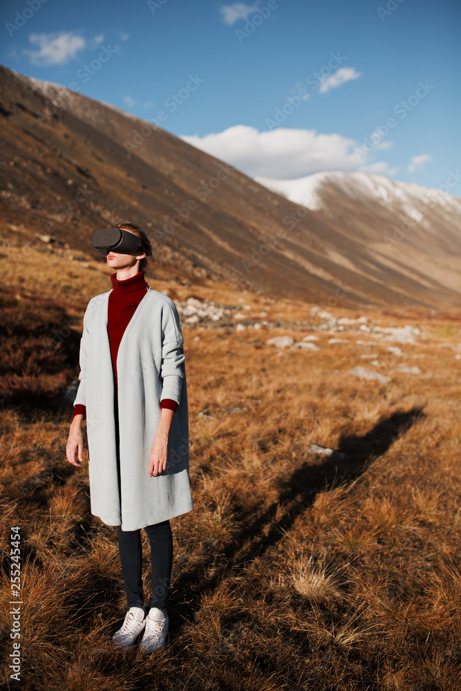 Naklejka premium Woman in virtual reality. Mountain landscape at background.