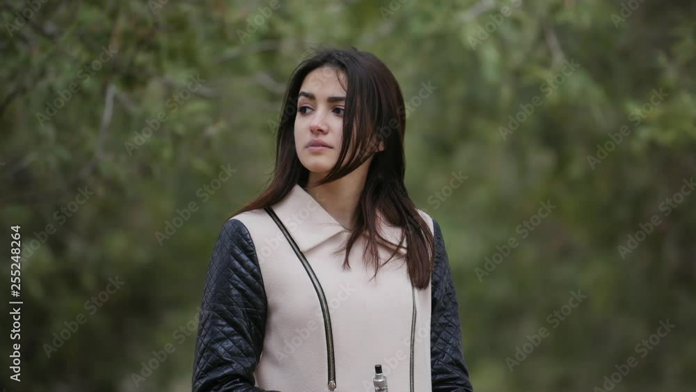 beautiful young girl vaping e-cigarette in the forest,closeup beautiful young girl vaping e-cigarette in the forest,closeup