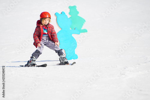 Child girl skiing in mountains. Active kid with safety helmet and goggles. Ski race for young children. Kids ski lesson in alpine school. Little skier racing in snow