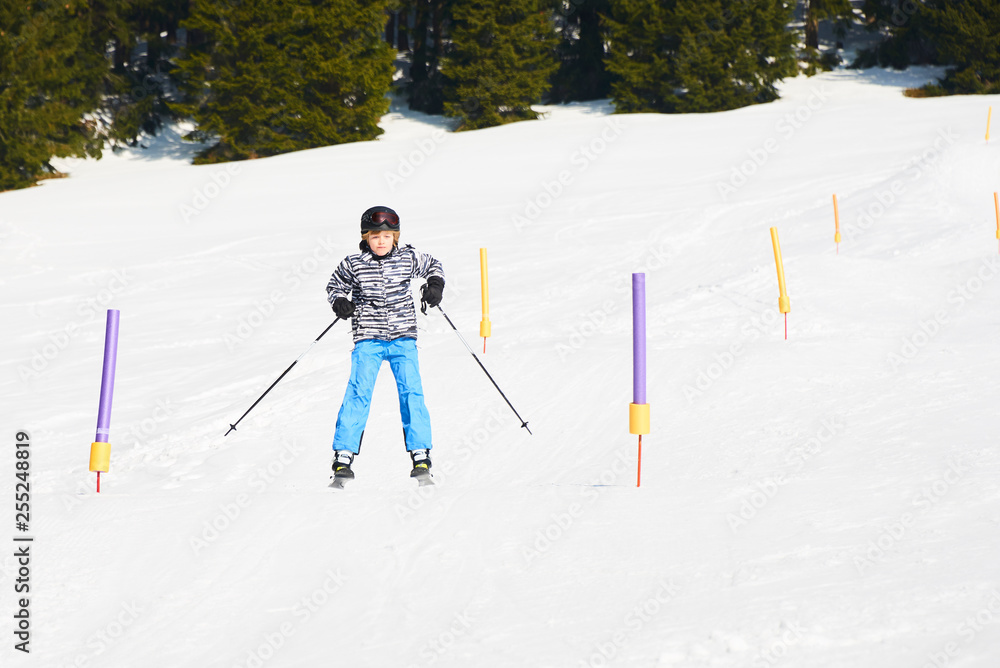 Child skiing in mountains. Active teenager kid with safety helmet and goggles. Ski race for young children. Winter sport for family. Kids ski lesson in alpine school. Young skier racing in snow
