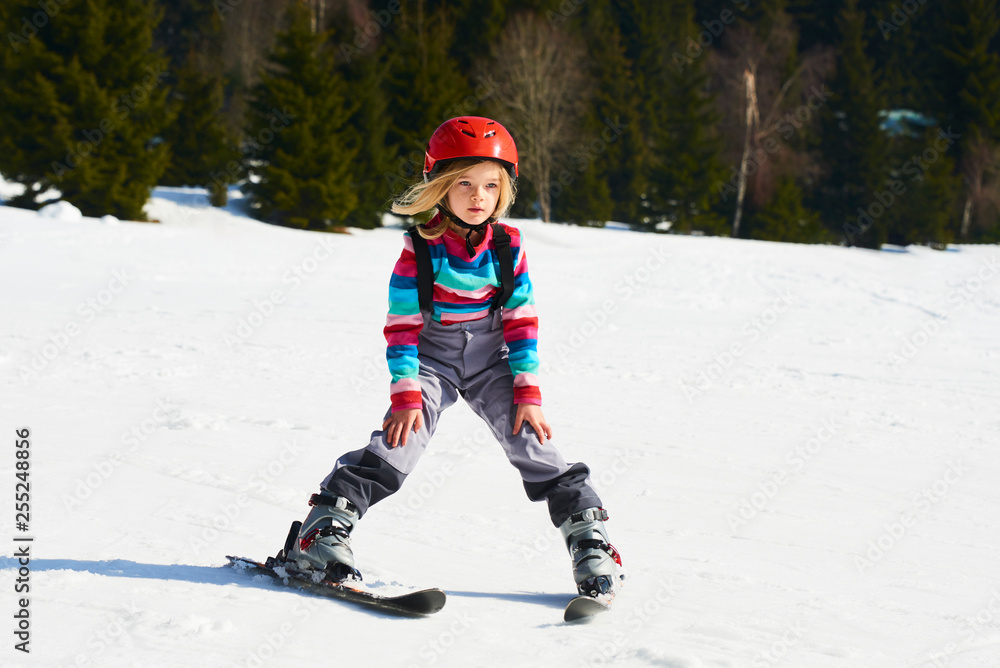 Child girl skiing in mountains. Active kid with safety helmet and goggles. Ski race for young children. Kids ski lesson in alpine school. Little skier racing in snow Child girl skiing in mountains. Active kid with safety helmet and goggles. Ski race for young children. Kids ski lesson in alpine school. Little skier racing in snow