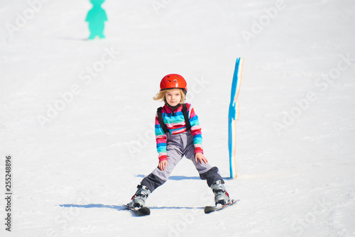 Child girl skiing in mountains. Active kid with safety helmet and goggles. Ski race for young children. Kids ski lesson in alpine school. Little skier racing in snow