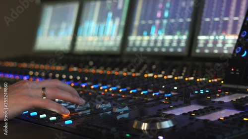 A man works in a recording studio on a mixing console. Hands close up