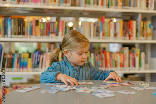 Little girl playing puzzle in a library