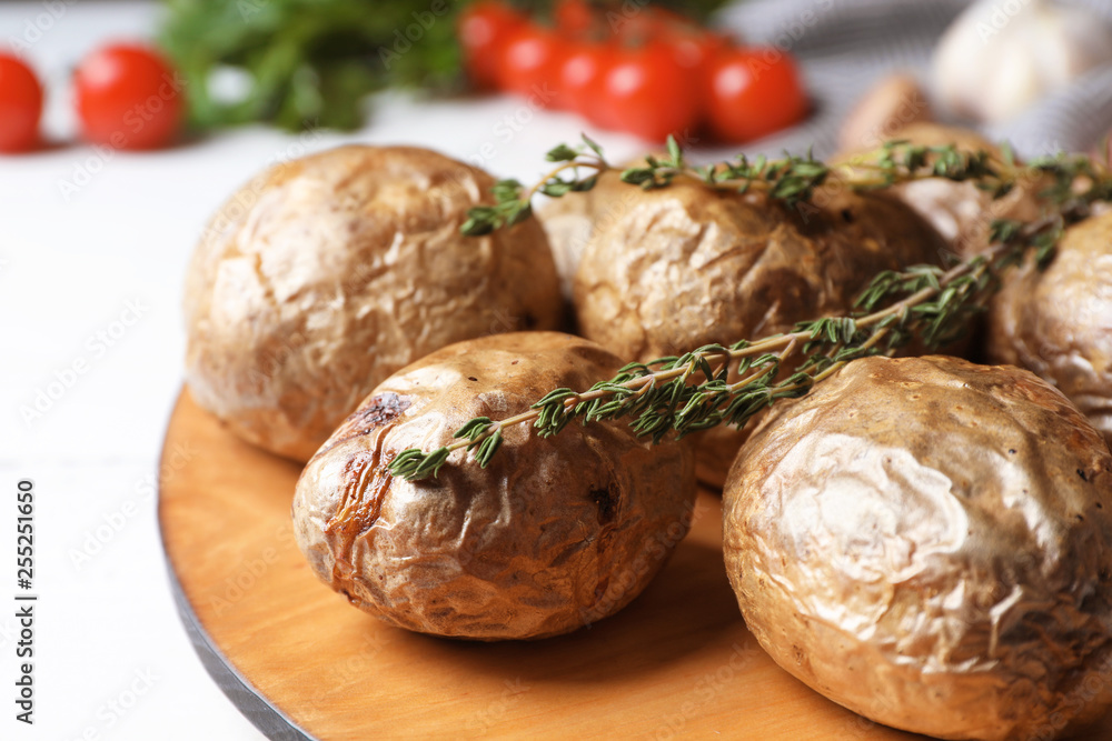Board with tasty baked jacket potatoes on table, closeup Board with tasty baked jacket potatoes on table, closeup