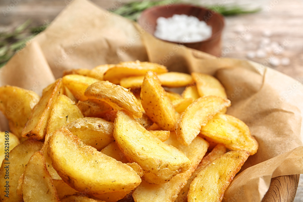 Delicious baked potato wedges on parchment paper, closeup Delicious baked potato wedges on parchment paper, closeup