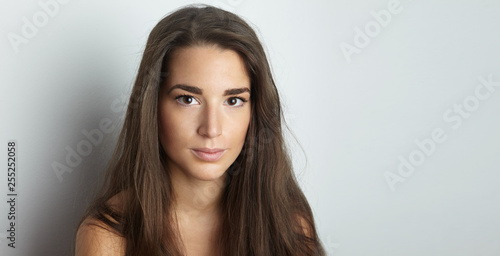 Portrait of handsome pretty young woman with long hair at empty white background wall. Space for copy paste text message