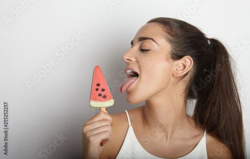 Fashion smiling young woman holding a slice of watermelon in the form of ice cream over a white background