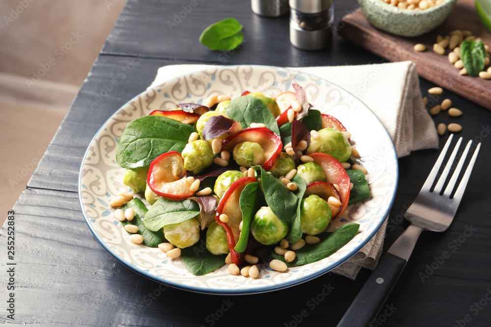 Plate of delicious salad with Brussels sprouts and roasted apples on wooden table Plate of delicious salad with Brussels sprouts and roasted apples on wooden table
