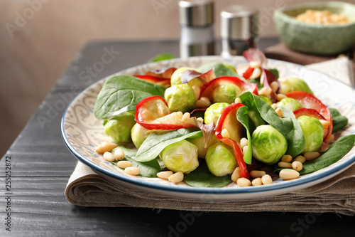 Plate of delicious salad with Brussels sprouts and roasted apples on wooden table