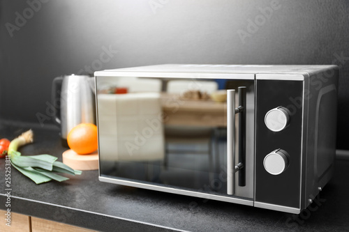 Modern microwave oven and ingredients on table in kitchen photo