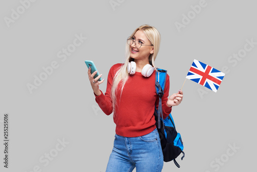 Online Education, foreign language translator, english, student - smiling blond woman in headphones holding mobile phone and British flag. Distance learning