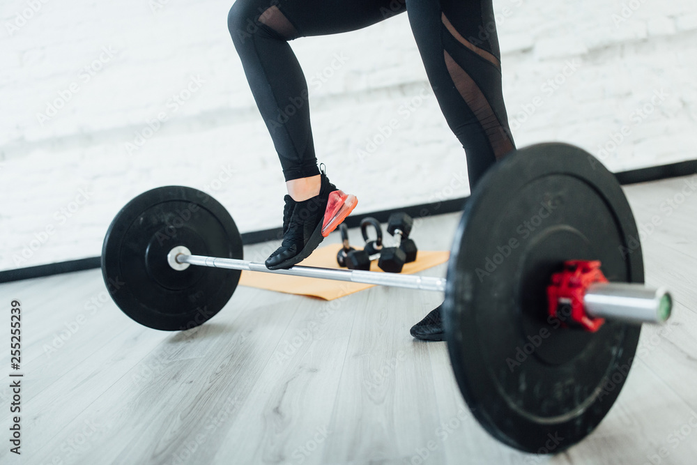 Portrait of legs sporty woman with barbell. Isolatet on gray floor! Lifestyle. Portrait of legs sporty woman with barbell. Isolatet on gray floor! Lifestyle.