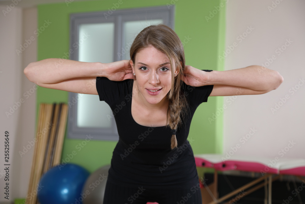Smiling Fitness Instructor Warming Up In The Gym, Doing Bending Exercises With Hands On Her Head Smiling Fitness Instructor Warming Up In The Gym, Doing Bending Exercises With Hands On Her Head