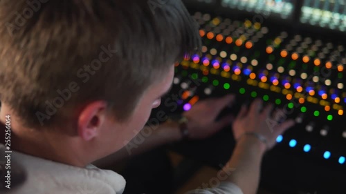 A man works in a recording studio on a mixing console.