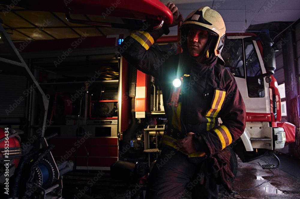 Fireman wearing a protective uniform with flashlight included working in a fire station garage Fireman wearing a protective uniform with flashlight included working in a fire station garage