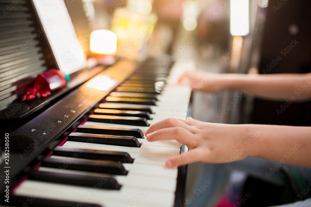 Obraz premium closeup kid's hand playing piano on stage, favorite classical music, the concept of musical instrument