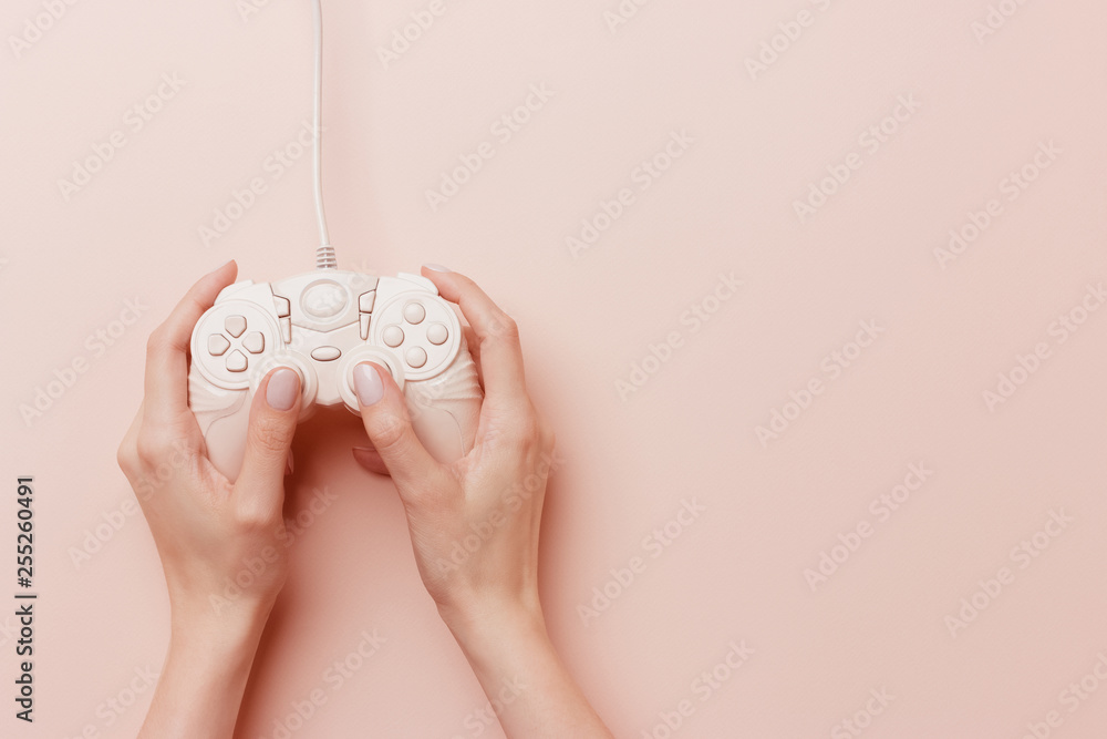 Female hands holding a pink joystick and play video game isolated on a pink background Female hands holding a pink joystick and play video game isolated on a pink background