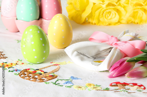 Easter place setting on an elegant embroidered linen table cloth with pink tulips and Easter eggs.   