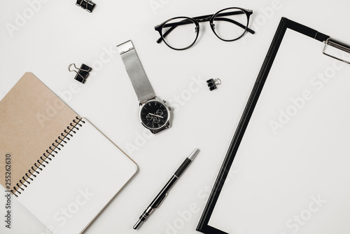 Workspace with blank clip board, watch, office supplies, pen and eyeglasses on white background. Flat lay, top view office table desk. Copy space